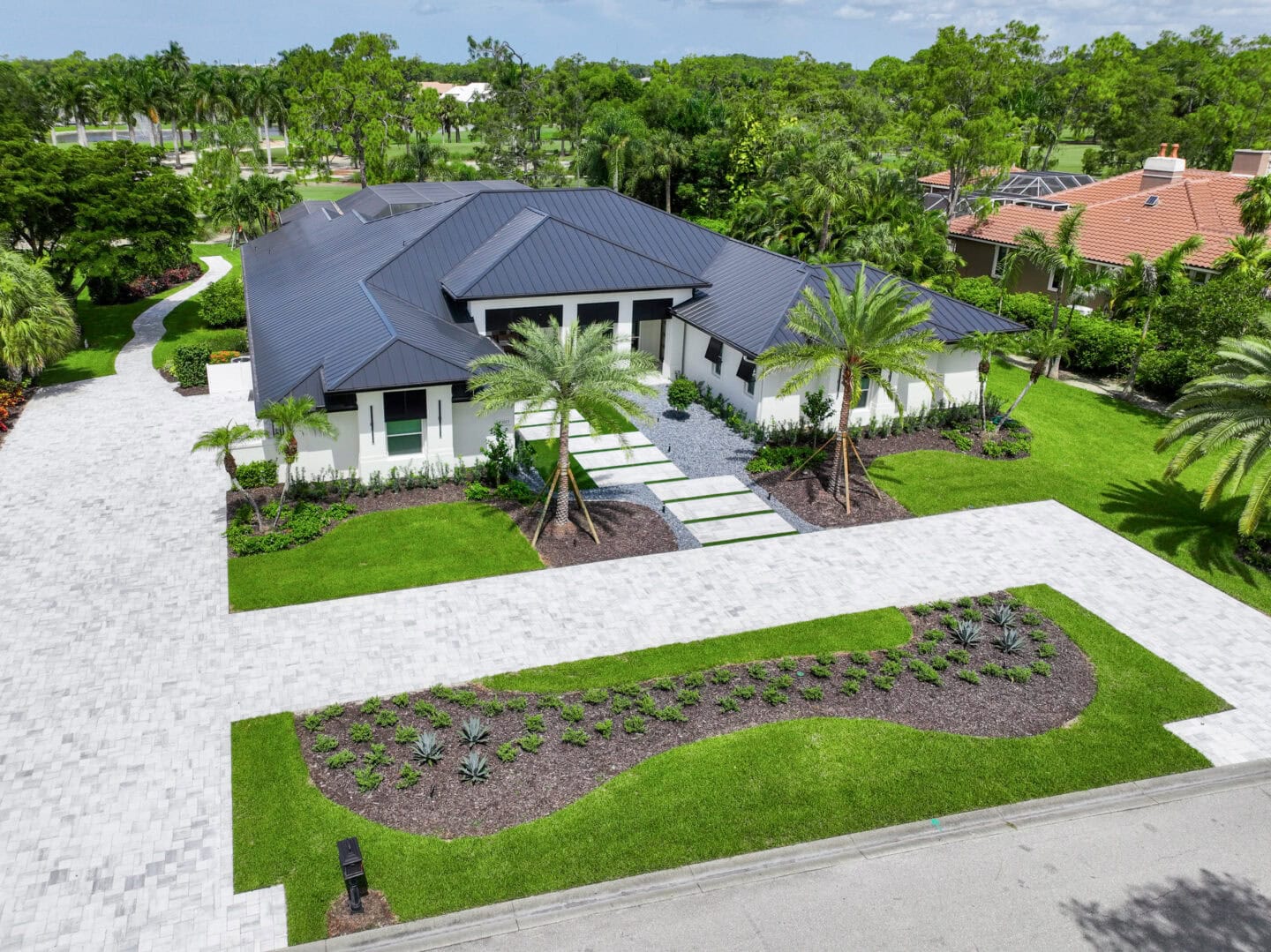 paved driveway and walkways Modern home with lush landscaping.