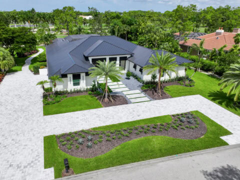 paved driveway and walkways Modern home with lush landscaping.