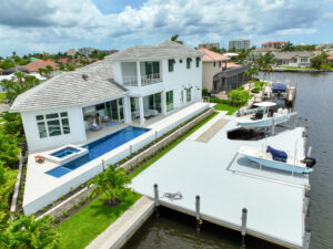 Modern waterfront home with boats, paved pool deck area